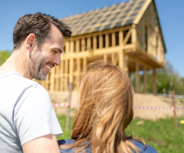Couple looking at their new house under construction, planning future and dreaming
